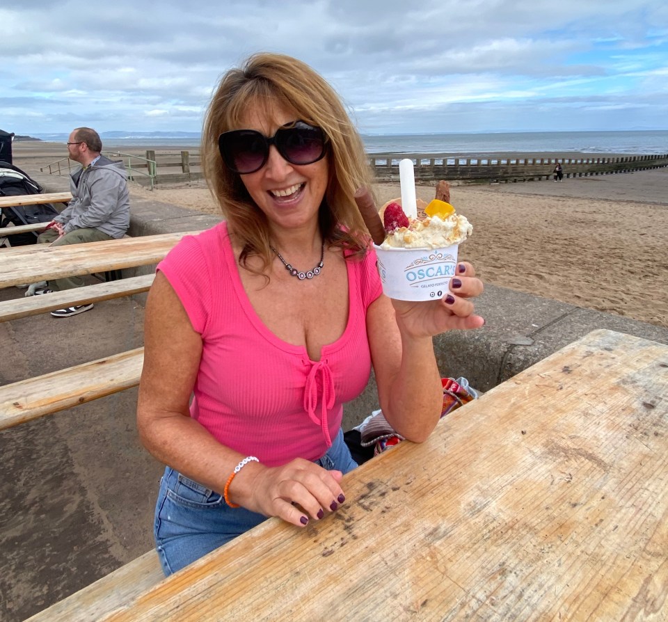 a woman sitting at a picnic table holding a bowl of ice cream