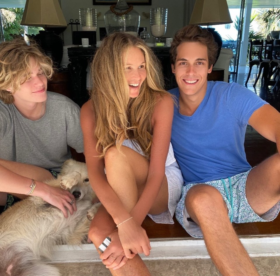 a woman sits next to two boys and a dog