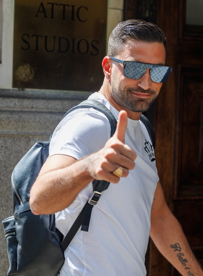 a man giving a thumbs up in front of a sign that says attic studios