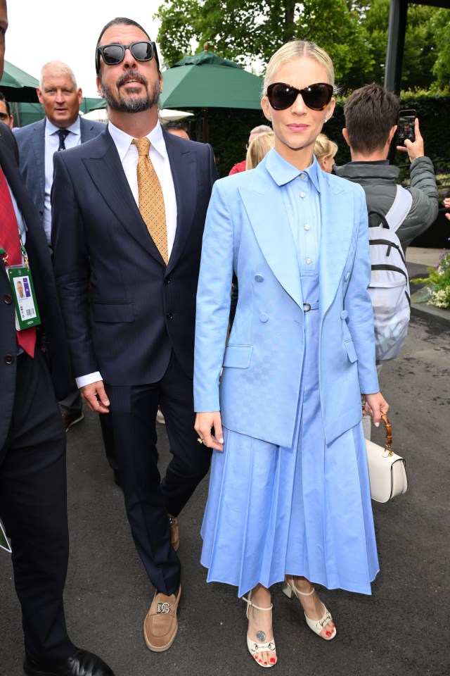 a man in a denim jacket holds a woman in a red dress