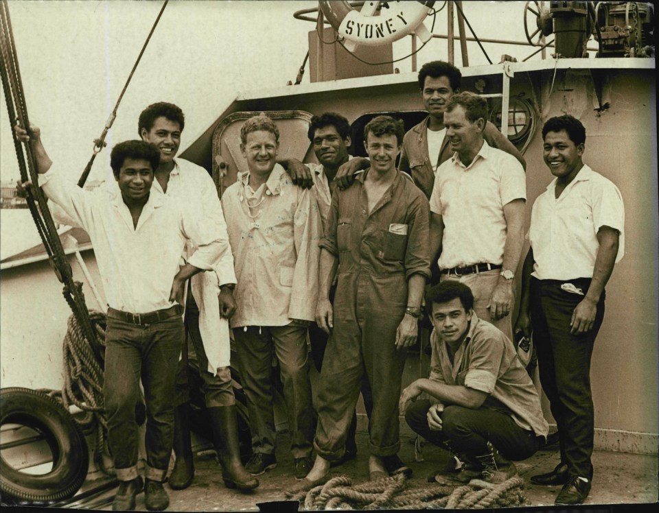 a group of men pose for a photo in front of a sydney ship