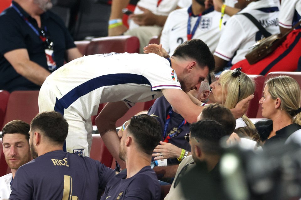 a man in a rice jersey kisses a woman on the cheek