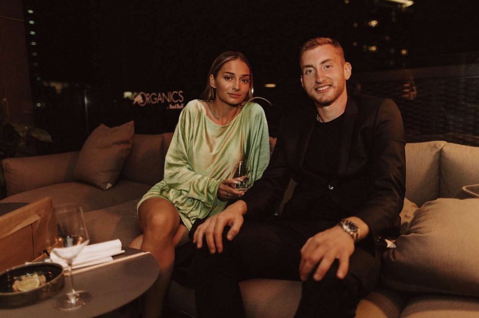 a man and a woman sit on a couch in front of a sign that says organics