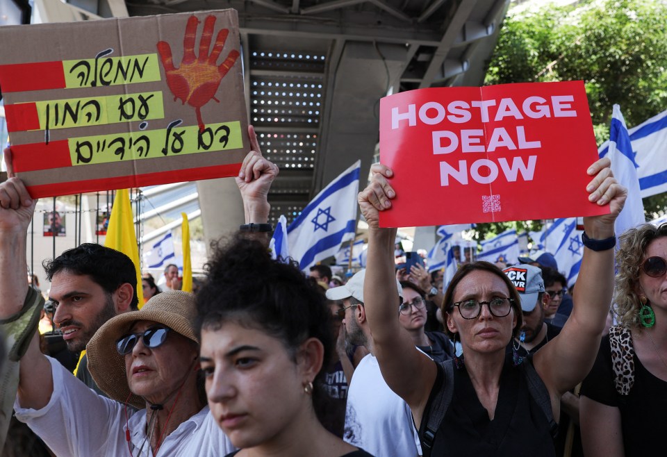 Demonstrators hold signs together outside the Defence Ministry in Tel Aviv