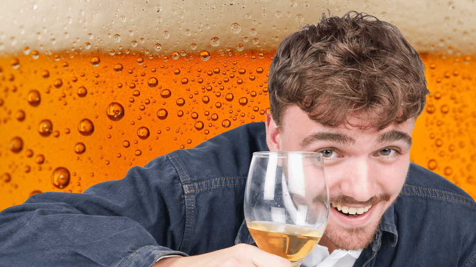 a man holds a glass of beer in front of a glass of beer