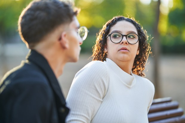 a man and a woman are sitting on a bench and the woman is wearing glasses