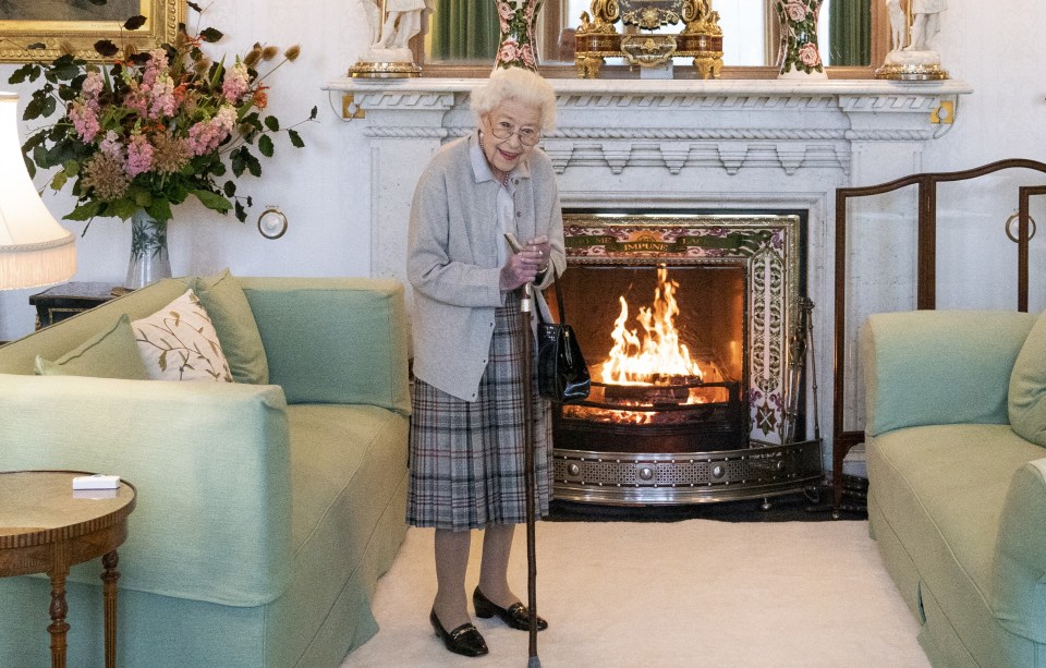 an elderly woman stands in front of a fireplace in a living room