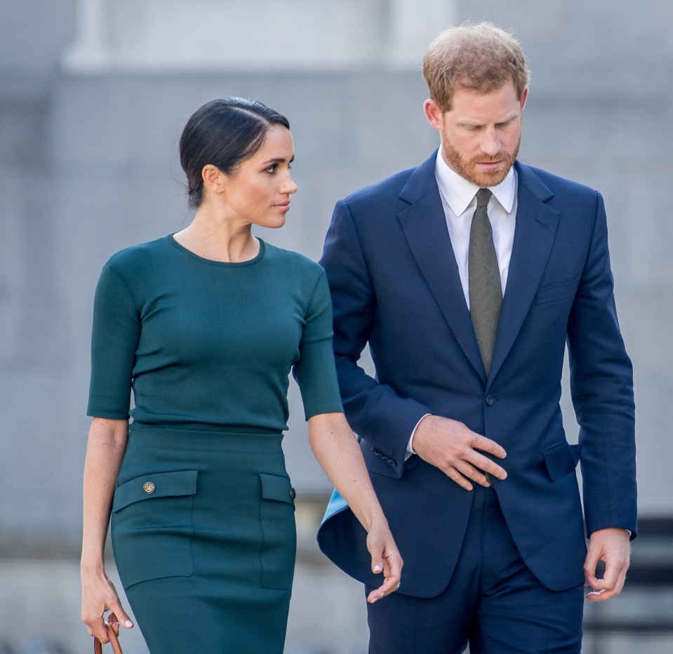 a man in a suit stands next to a woman in a green dress