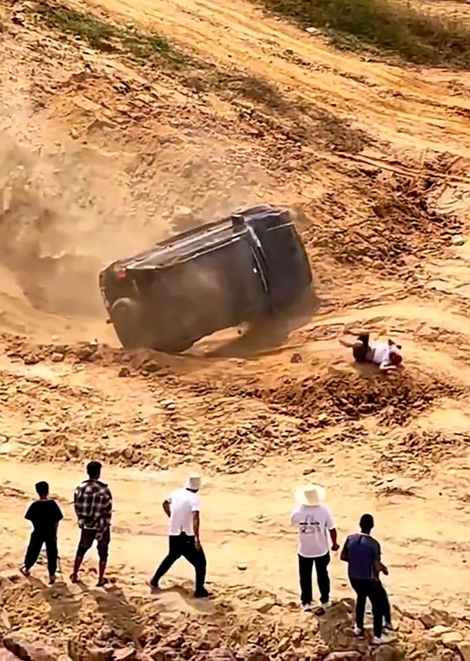 a group of people standing around a car that has rolled over