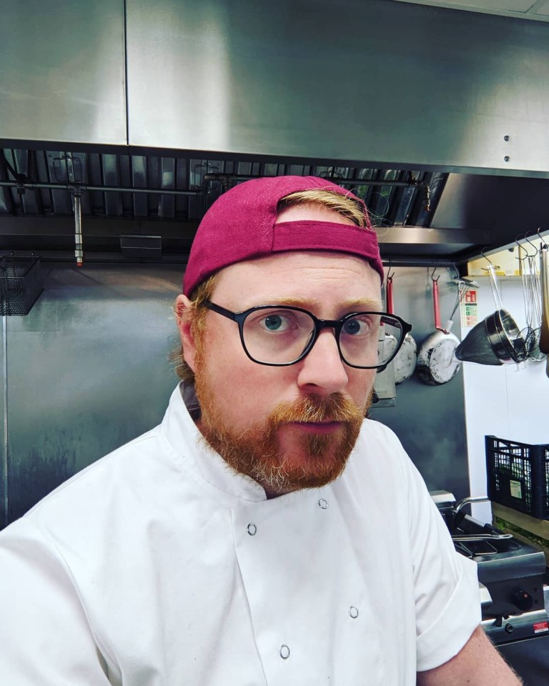 a man wearing glasses and a pink hat stands in a kitchen