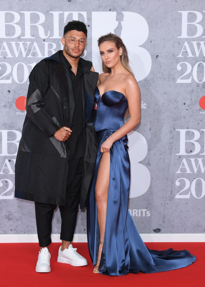 a man and a woman pose on the red carpet at the brit awards