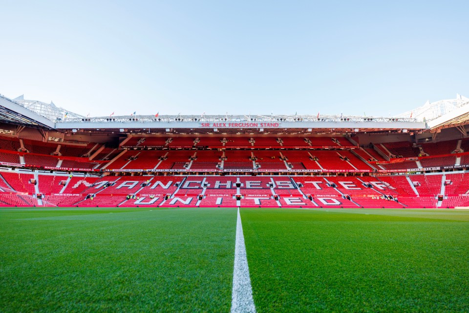 an empty manchester united stadium with red seats