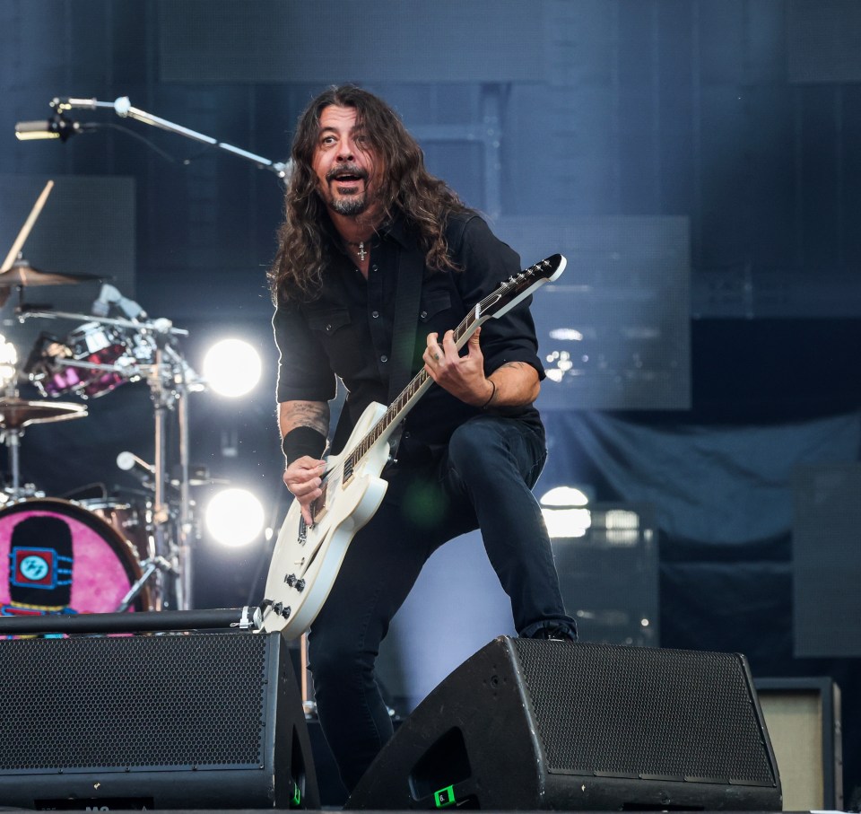 a man playing a guitar on stage with a drummer behind him