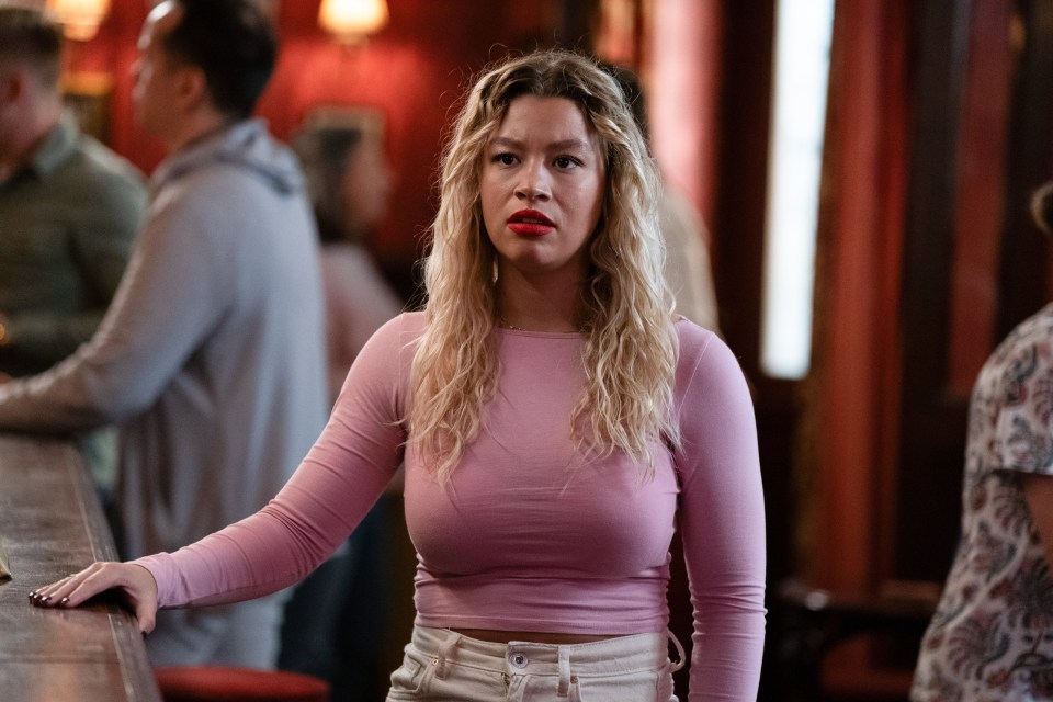 a woman in a pink top is leaning on a bar