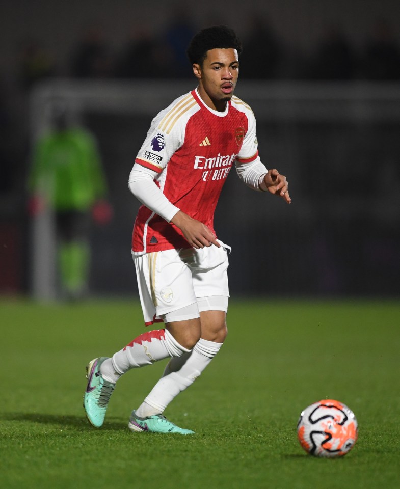 a soccer player wearing a red emirates jersey runs with the ball