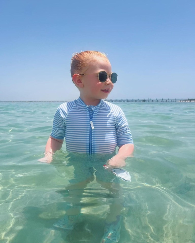 a little boy wearing sunglasses is standing in the water