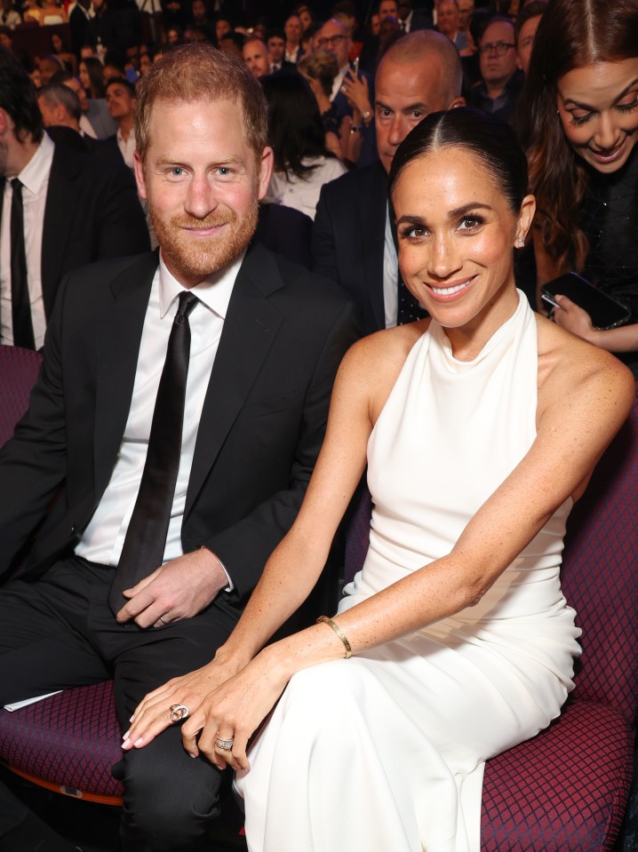 a man in a suit and tie sits next to a woman in a white dress