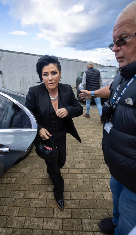 a woman in a black suit is getting out of a car