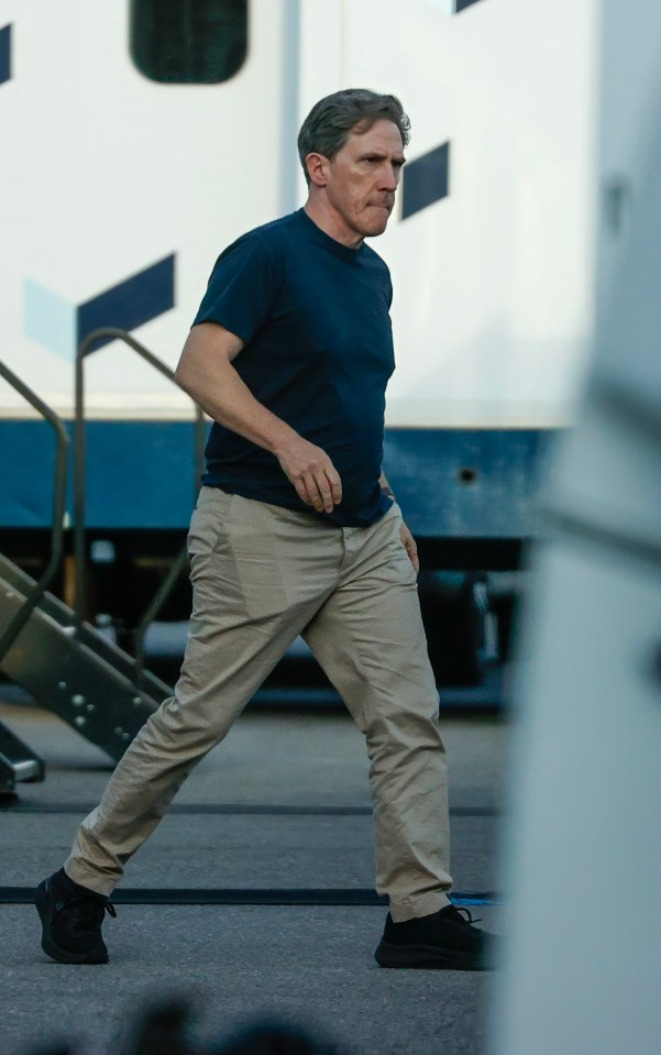 a man in a blue shirt and khaki pants is walking