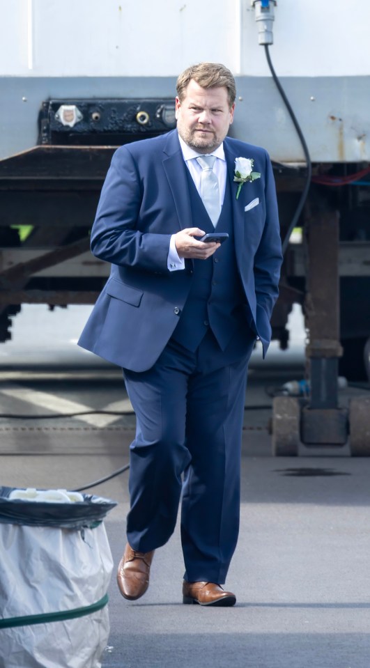 a man in a blue suit is holding a cell phone