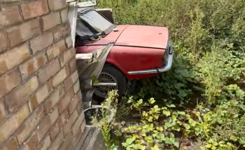 a red car is leaning against a brick wall