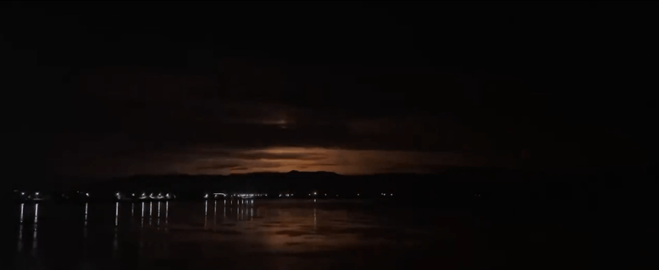 lightning strikes over a body of water at night