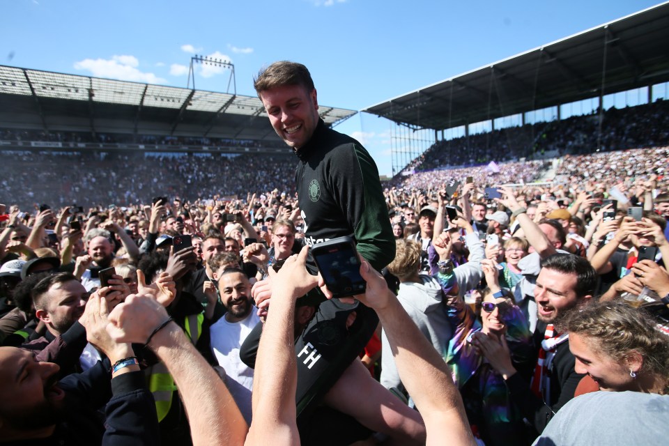 a man is being lifted in the air by a crowd and his shirt says fh