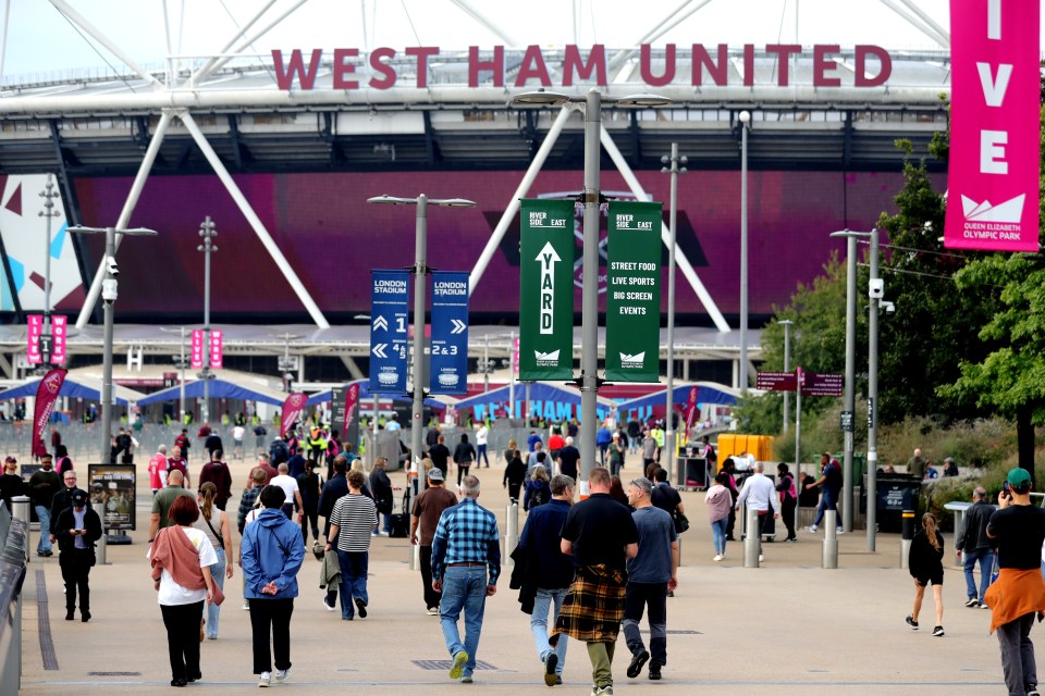 a crowd of people walking in front of the west ham united stadium