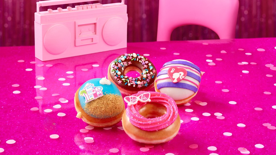 four barbie donuts are on a pink table