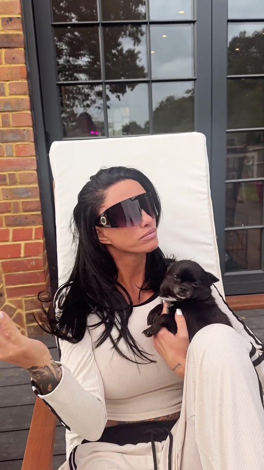 a woman wearing sunglasses holds a small black dog