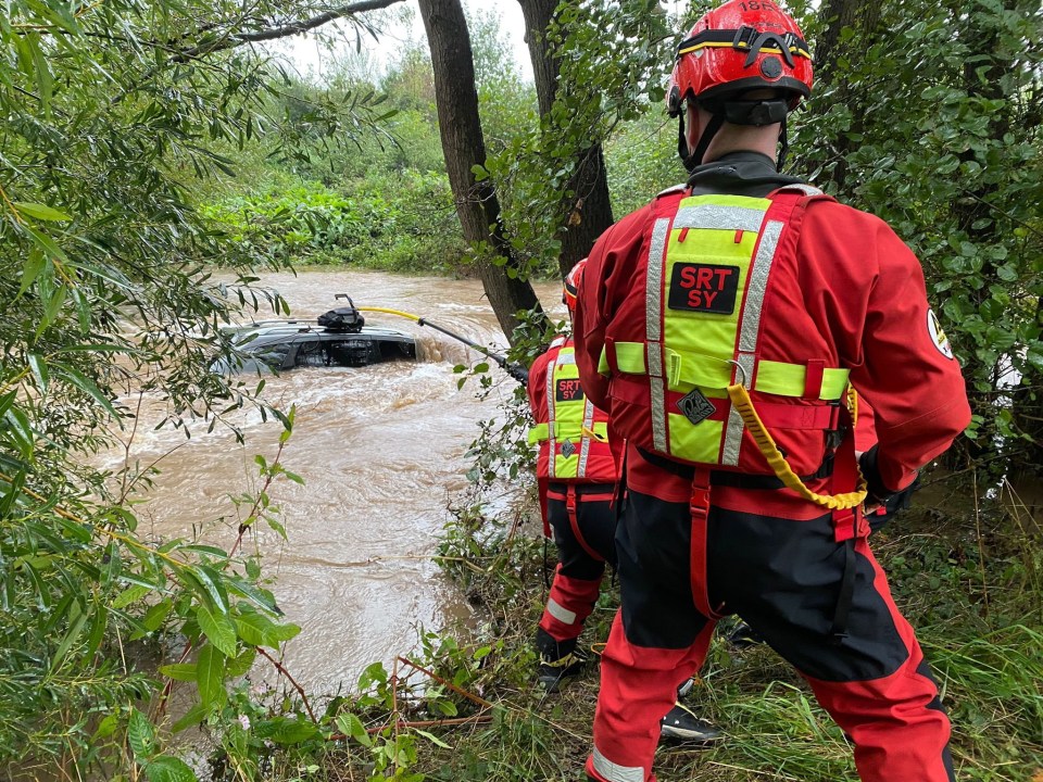 a man in a srt sy vest stands in a flooded area