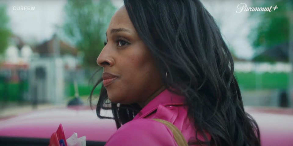 a woman in a pink jacket is sitting in a car with a paramount logo behind her