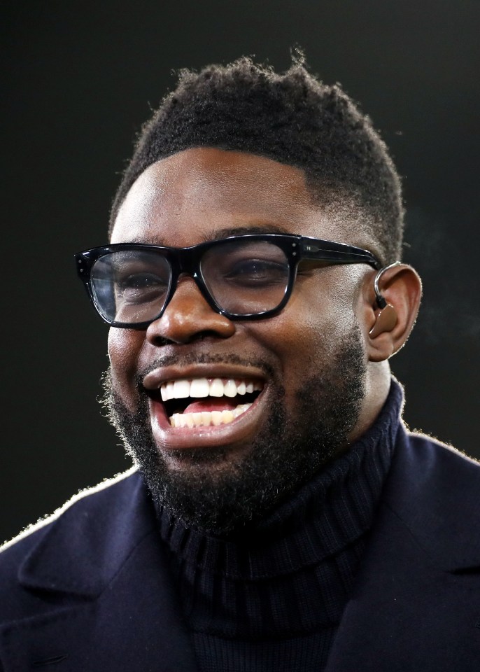 a man wearing glasses and a turtleneck is smiling