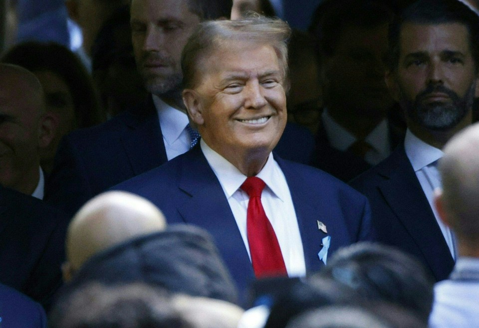 a man in a suit and tie smiles in front of a crowd