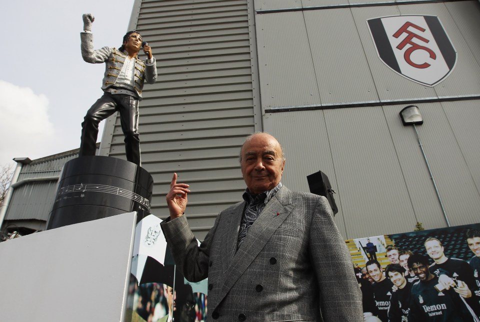 a man in a suit stands in front of a statue of michael jackson