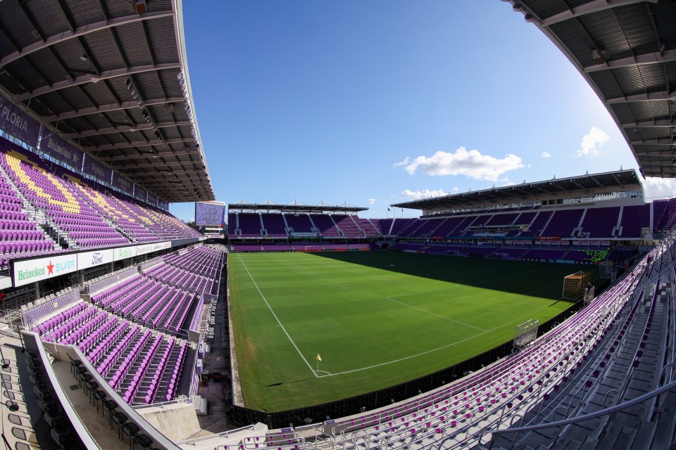 a soccer stadium with purple seats and a heineken sign