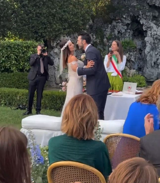 a bride and groom kiss during their wedding ceremony