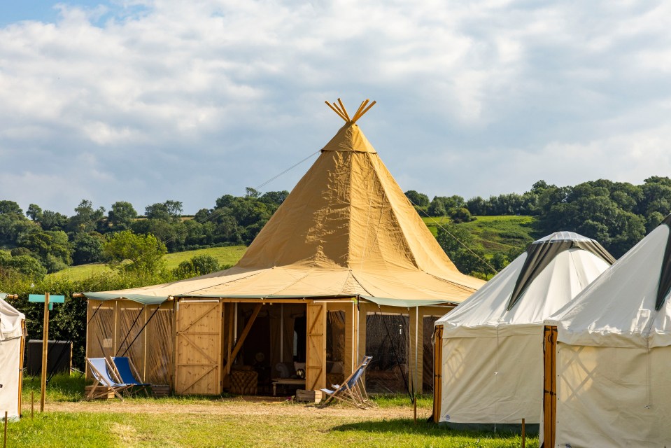 a tent with a teepee shaped top sits in the middle of a field