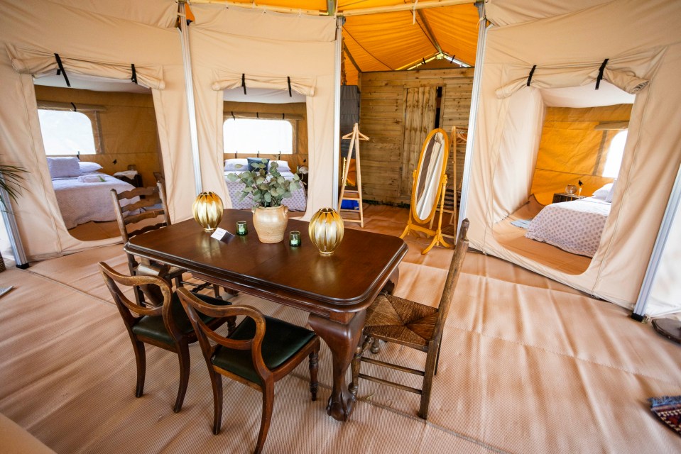 a table and chairs in a tent with a vase of flowers on it