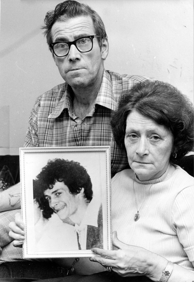 a man and a woman holding a framed picture of their son