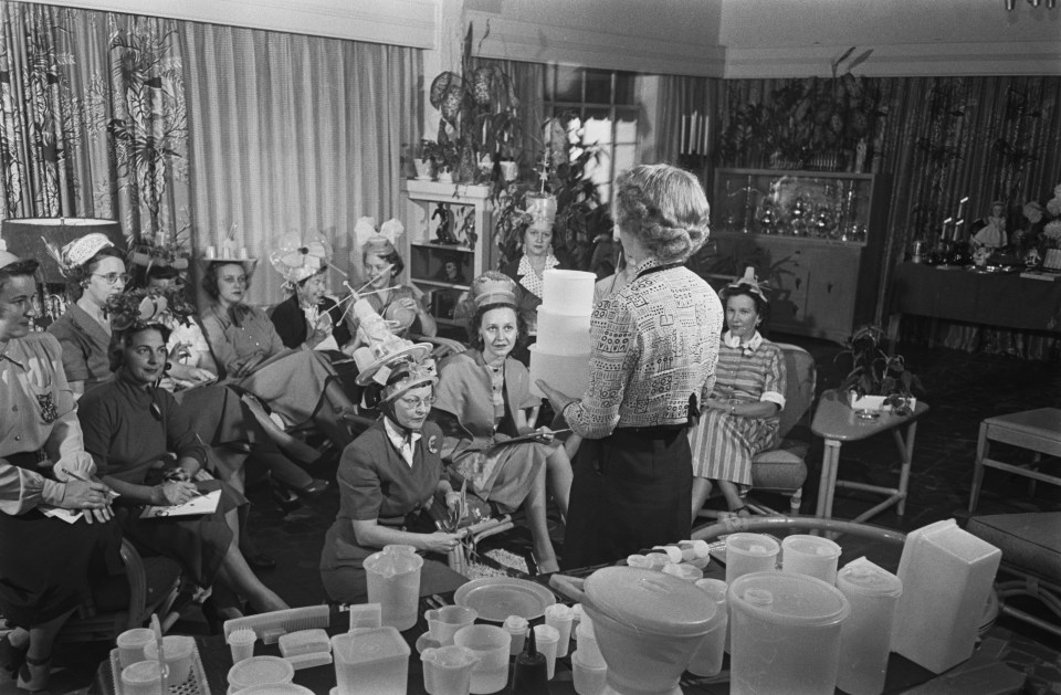 a woman stands in front of a group of women holding a tupperware container