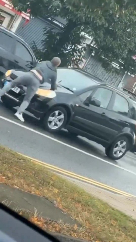 The man in the white trainers tries to keep filming on his phone as the motorist starts to drive off