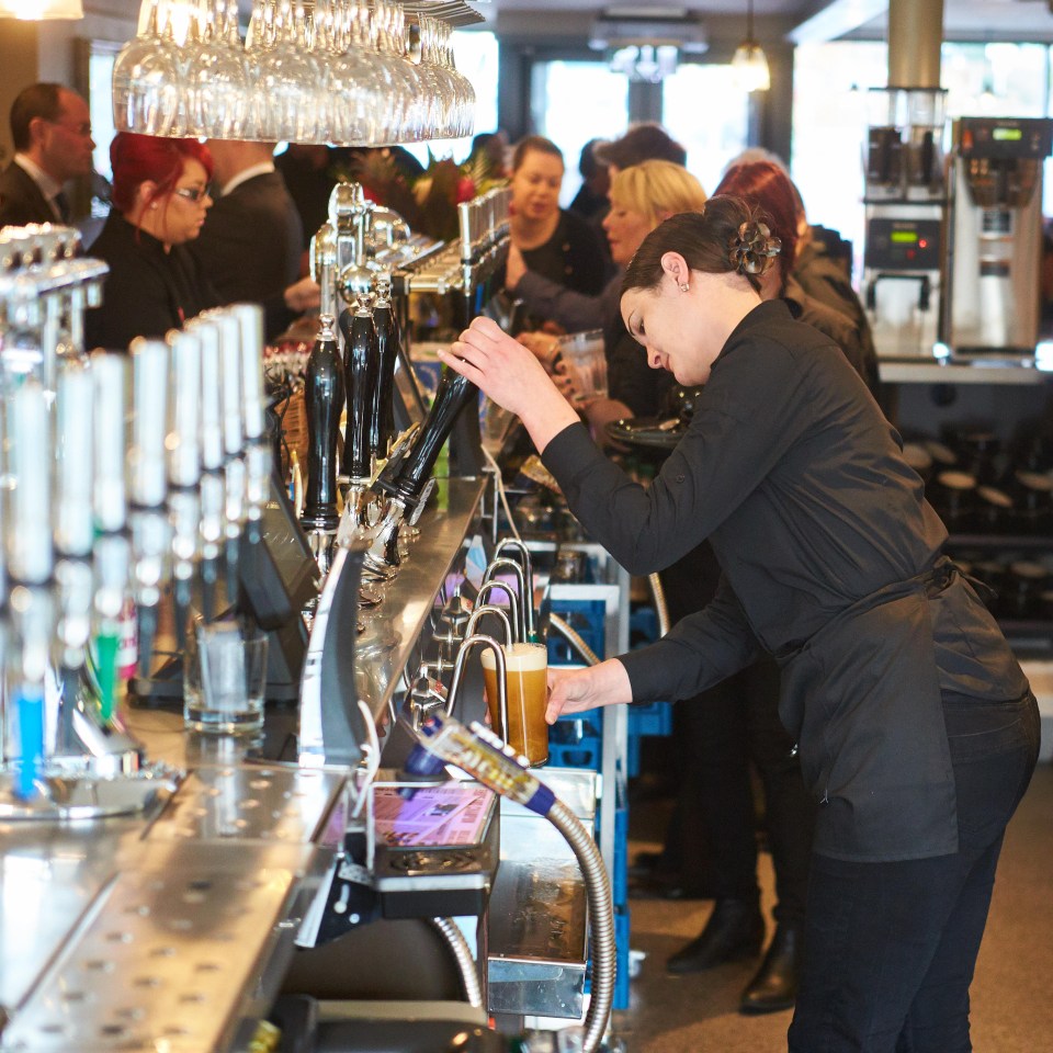 a bartender pours a beer into a glass