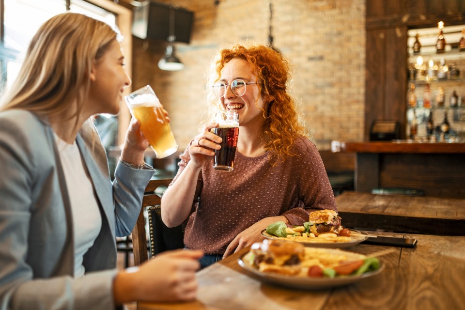 Happy Female Friends Having meal And Beer And Laughing