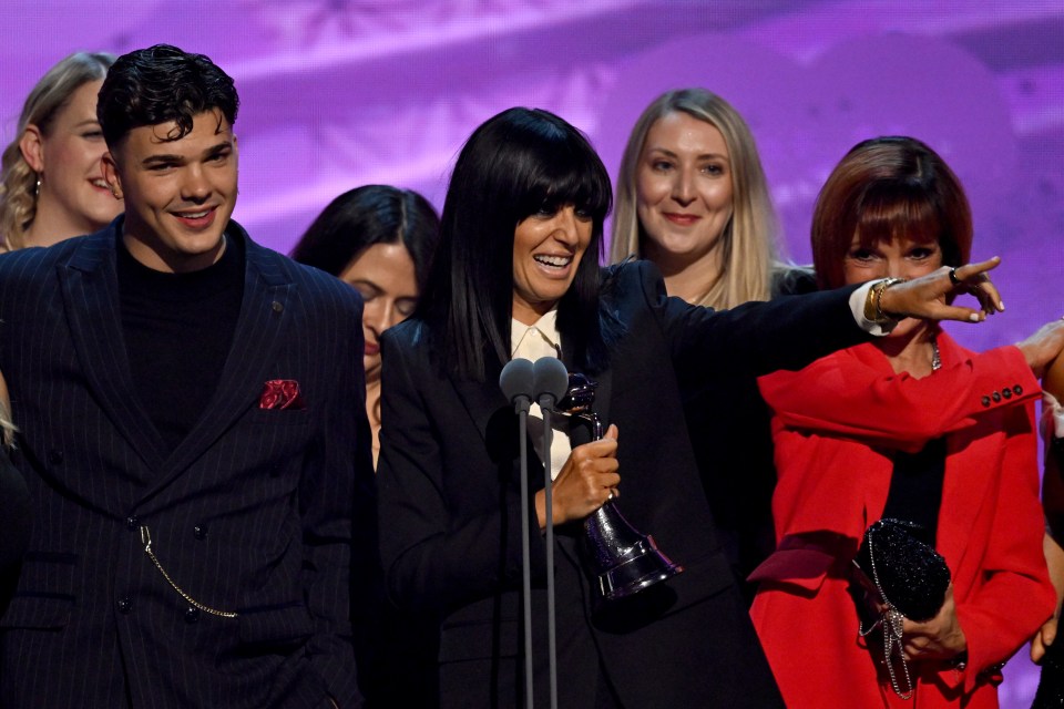 a group of people standing in front of a microphone with one woman pointing