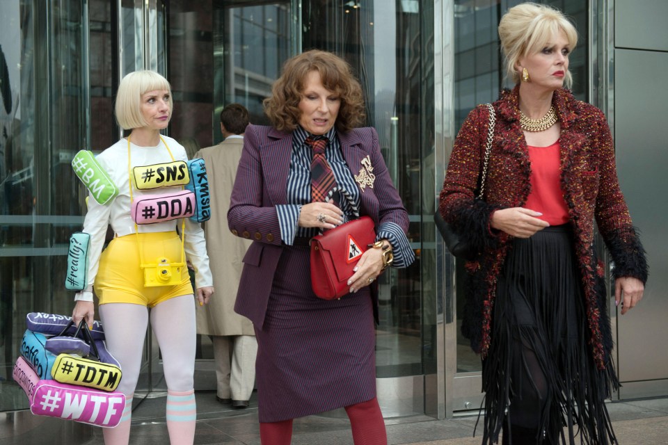 three women are standing in front of a building and one of them is wearing a shirt that says #sns