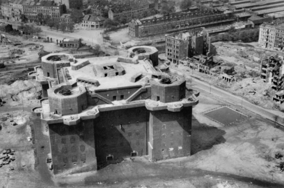 a black and white photo of a castle with a few buildings in the background