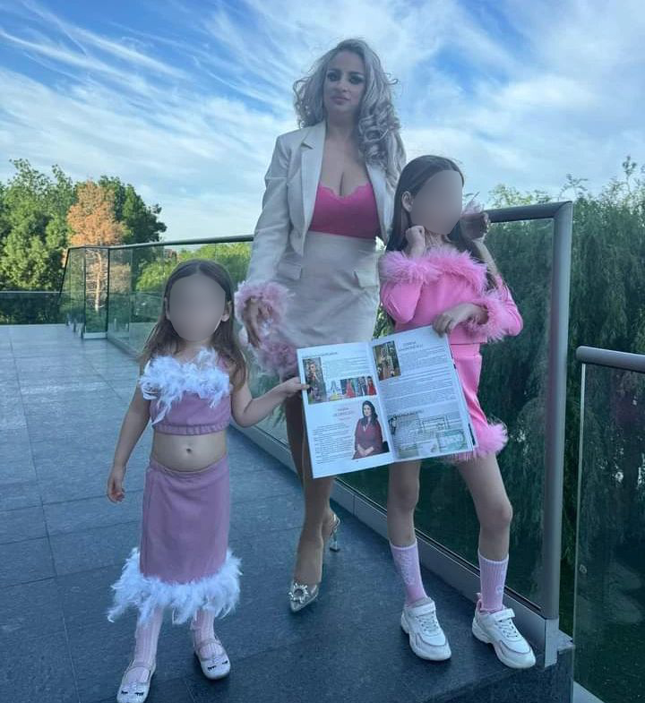 a woman is standing next to two little girls holding a magazine