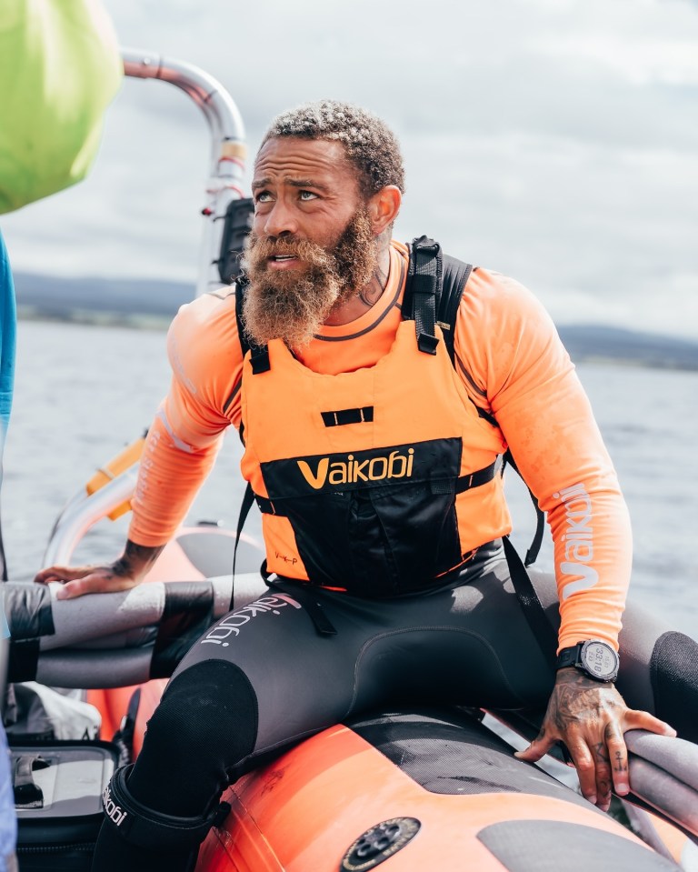 a man with a beard wearing an orange vest that says vaikodi