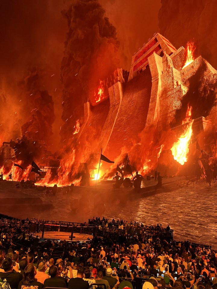 a crowd of people are watching a large building burn